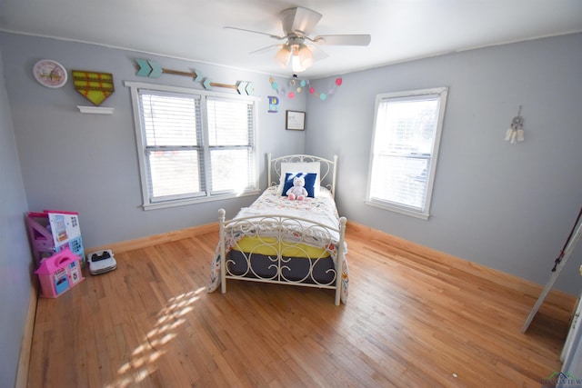 bedroom with ceiling fan, wood-type flooring, and multiple windows