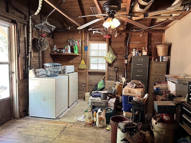 laundry room with a healthy amount of sunlight, washing machine and dryer, and wooden walls