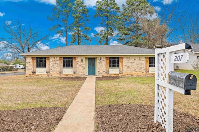 single story home featuring roof with shingles, a front yard, and brick siding