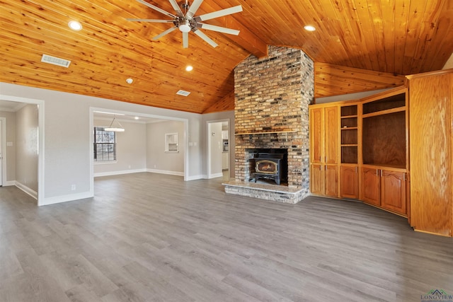 unfurnished living room featuring hardwood / wood-style floors, a wood stove, ceiling fan, and wooden ceiling