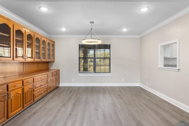 unfurnished dining area featuring light wood-type flooring and crown molding