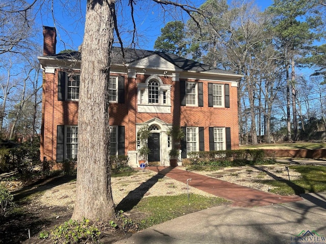 colonial home featuring brick siding and a chimney