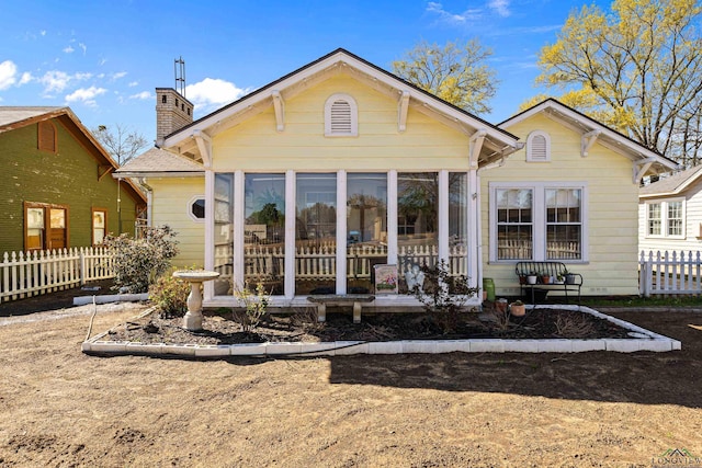 rear view of property with a sunroom, fence, and a chimney