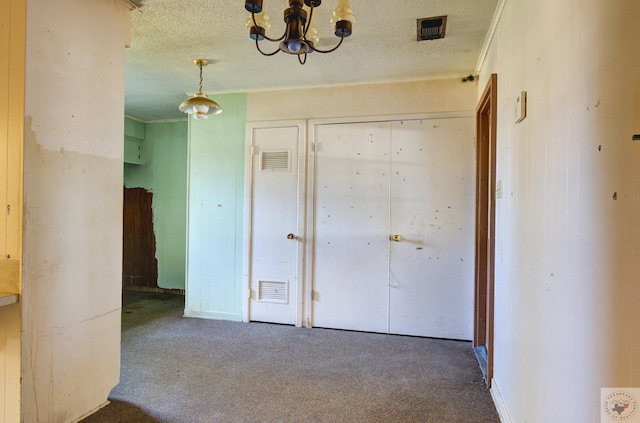 interior space with a chandelier, carpet, and a textured ceiling