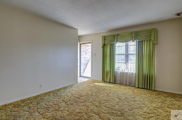 unfurnished room with carpet floors, a healthy amount of sunlight, and a textured ceiling