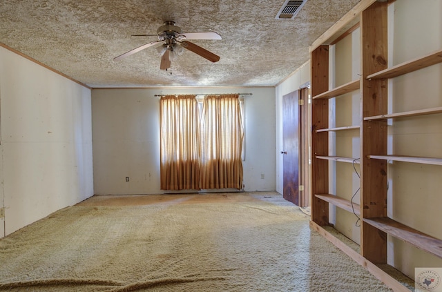 spare room featuring ceiling fan, ornamental molding, carpet floors, and a textured ceiling