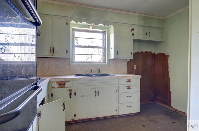 kitchen with white cabinetry, sink, ornamental molding, and decorative backsplash