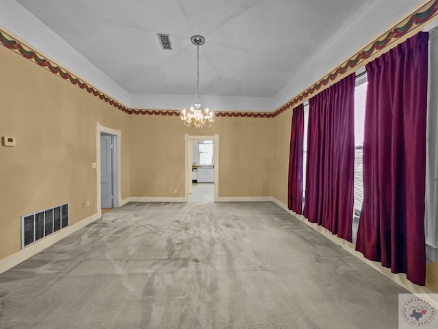 spare room featuring a wealth of natural light, carpet, and a notable chandelier