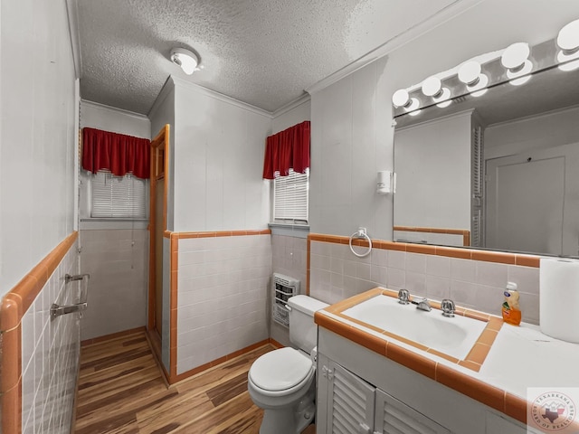 bathroom with a textured ceiling, wood-type flooring, vanity, tile walls, and crown molding