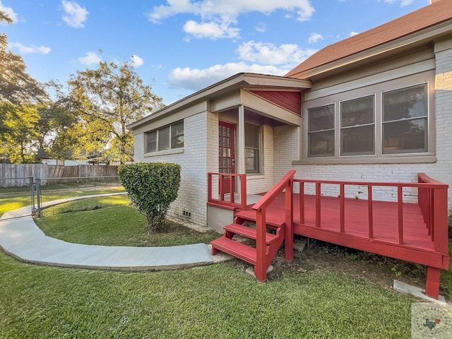 view of exterior entry with a deck and a yard