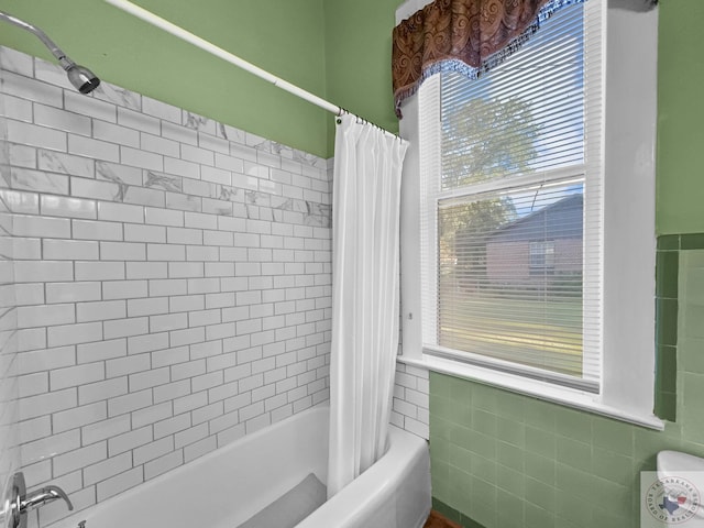 bathroom with shower / tub combo and tile walls