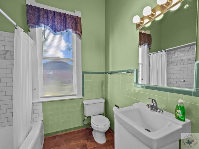 full bathroom featuring toilet, wood-type flooring, tile walls, sink, and shower / bathtub combination with curtain