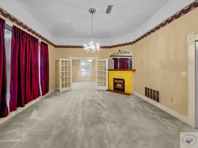 unfurnished living room featuring a notable chandelier, french doors, and carpet floors