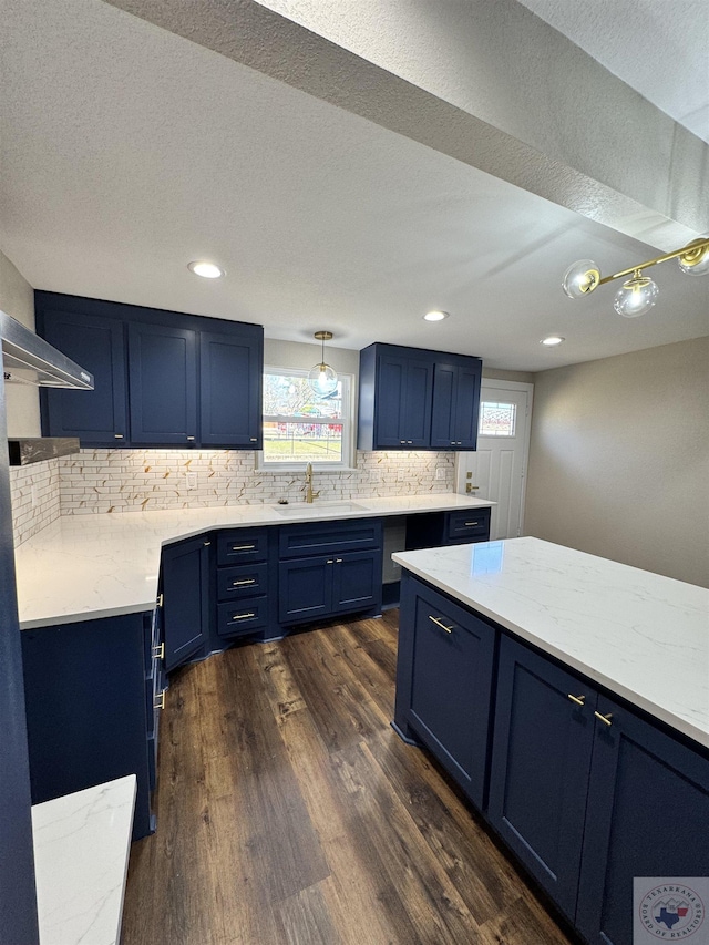 kitchen with blue cabinetry, tasteful backsplash, dark wood-type flooring, and a sink