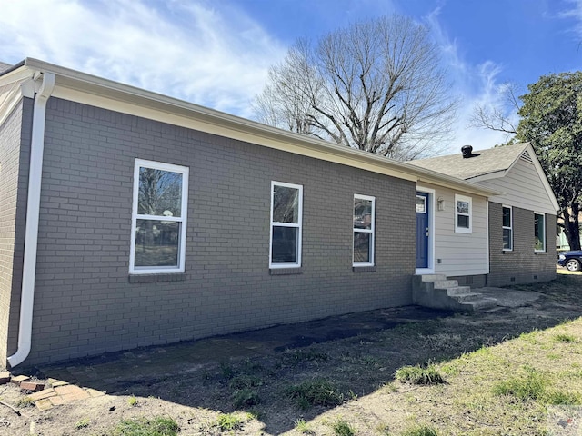 view of side of home featuring entry steps, crawl space, and brick siding