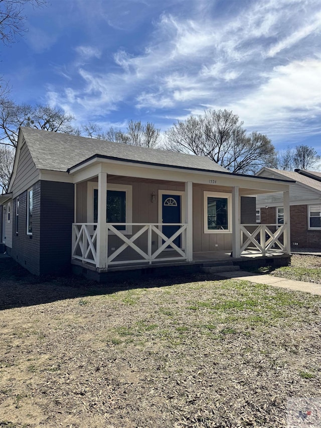 view of front of property with covered porch, roof with shingles, brick siding, and board and batten siding