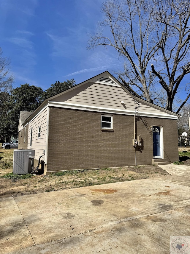 view of property exterior with central air condition unit, entry steps, and brick siding