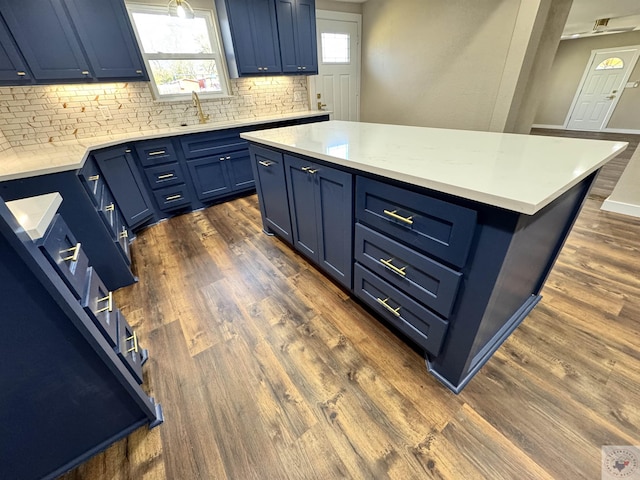 kitchen with blue cabinets, light countertops, backsplash, and dark wood-style floors