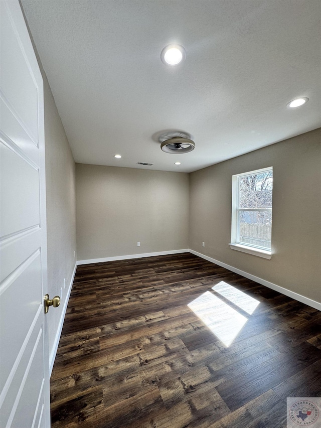 spare room with baseboards and dark wood-style flooring