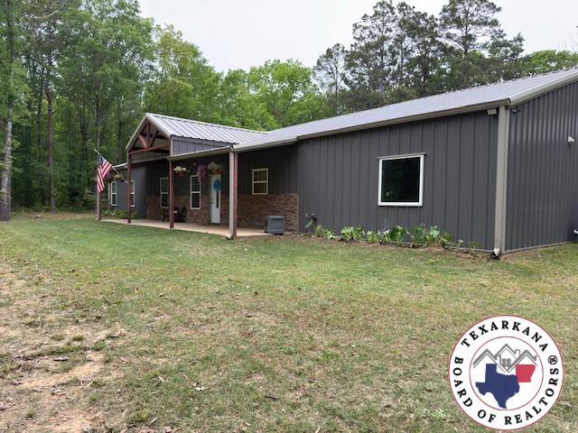 3059 Mc 22, Fouke, AR 71837 - view of front of house featuring board and batten siding, a front lawn, a metal roof, and a patio area