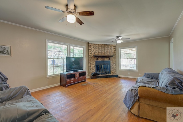 living room with a fireplace, light hardwood / wood-style floors, ceiling fan, and crown molding