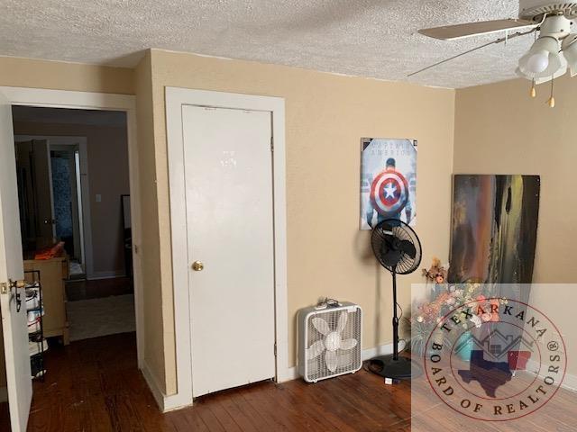 3812 Elizabeth St, Texarkana, TX 75501 - bedroom featuring wood finished floors, a textured ceiling, baseboards, and ceiling fan