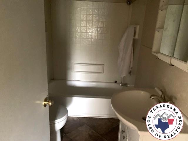 3812 Elizabeth St, Texarkana, TX 75501 - bathroom with vanity, toilet, and washtub / shower combination