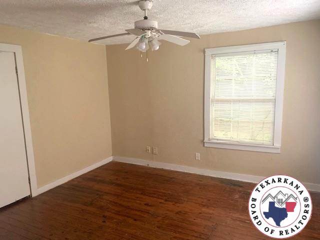 3812 Elizabeth St, Texarkana, TX 75501 - unfurnished room featuring a textured ceiling, a ceiling fan, wood finished floors, and baseboards