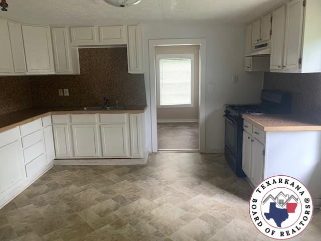 3812 Elizabeth St, Texarkana, TX 75501 - kitchen with black gas range oven, under cabinet range hood, backsplash, a sink, and stone finish floors
