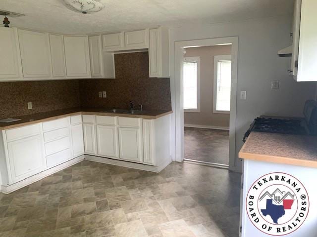3812 Elizabeth St, Texarkana, TX 75501 - kitchen featuring a sink, decorative backsplash, and white cabinets