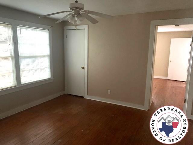 3812 Elizabeth St, Texarkana, TX 75501 - unfurnished bedroom with hardwood / wood-style floors, multiple windows, and baseboards