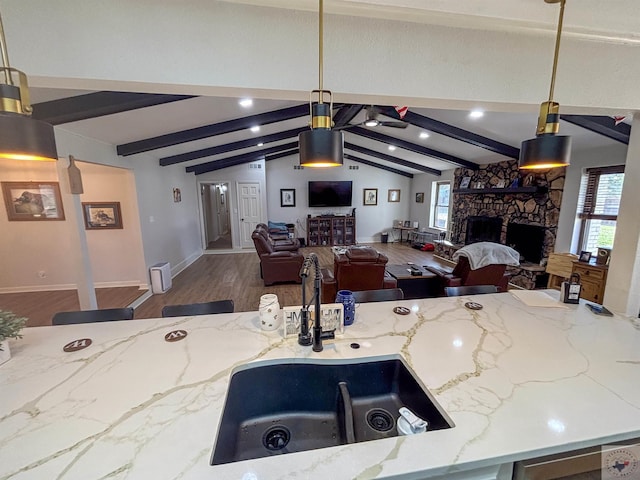 111 Oak St, New Boston, TX 75570 - kitchen featuring light stone counters, vaulted ceiling with beams, wood finished floors, a stone fireplace, and open floor plan
