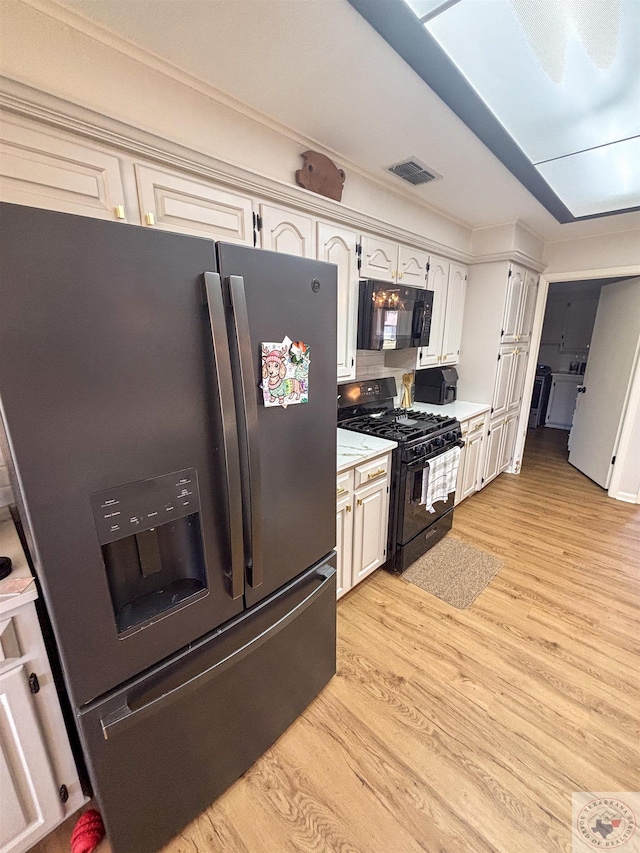 111 Oak St, New Boston, TX 75570 - kitchen featuring visible vents, light countertops, black appliances, and light wood-style floors