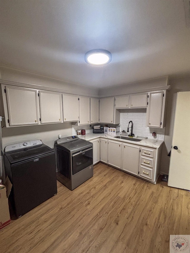 111 Oak St, New Boston, TX 75570 - kitchen with light countertops, washer and clothes dryer, tasteful backsplash, a sink, and light wood finished floors