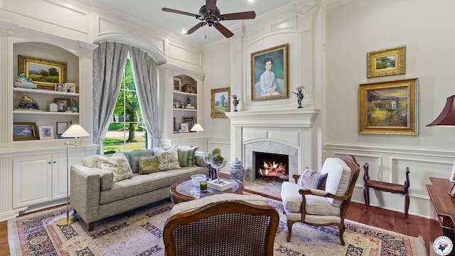 6804 Springwood Cir, Texarkana, TX 75503 - living area featuring built in shelves, a decorative wall, ceiling fan, wood finished floors, and a fireplace with flush hearth