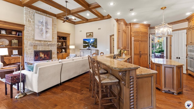 6804 Springwood Cir, Texarkana, TX 75503 - kitchen featuring dark wood finished floors, ceiling fan, a peninsula, a fireplace, and beamed ceiling