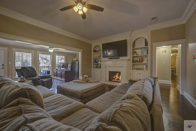 living room featuring a fireplace, built in features, dark hardwood / wood-style floors, and ornamental molding