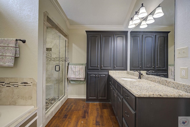 bathroom featuring crown molding, hardwood / wood-style flooring, walk in shower, and vanity