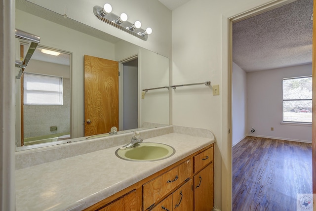 bathroom featuring vanity, wood finished floors, baseboards, and a textured ceiling