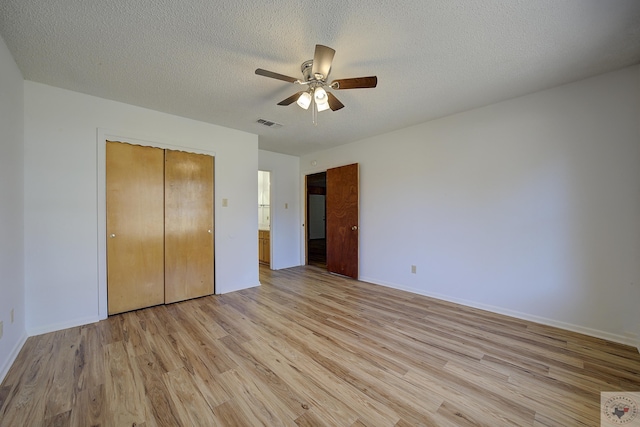 unfurnished bedroom with baseboards, light wood-style flooring, a closet, a textured ceiling, and a ceiling fan