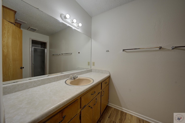 bathroom with visible vents, vanity, a stall shower, wood finished floors, and a textured ceiling