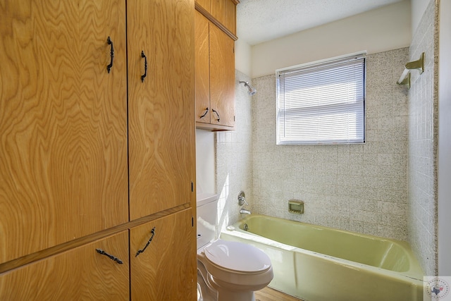 full bath with a textured ceiling, toilet, and shower / tub combination