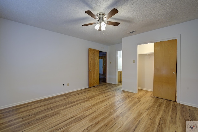 unfurnished bedroom featuring light wood-style flooring, baseboards, visible vents, and a textured ceiling