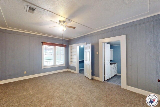 2006 Walnut St, Texarkana, TX 75501 - unfurnished bedroom featuring carpet, baseboards, a textured ceiling, wooden walls, and ensuite bathroom