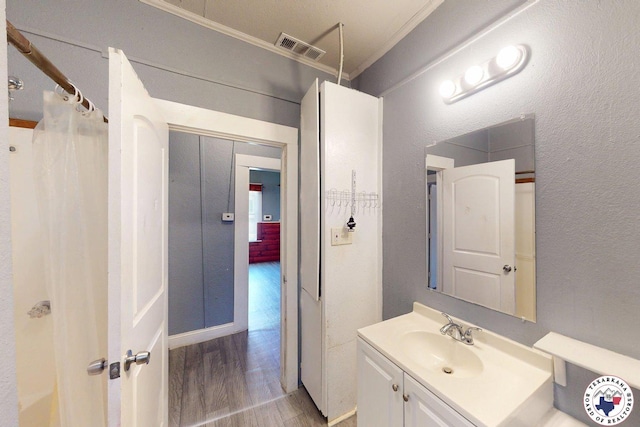 2006 Walnut St, Texarkana, TX 75501 - bathroom with wood finished floors, crown molding, vanity, and a shower with curtain