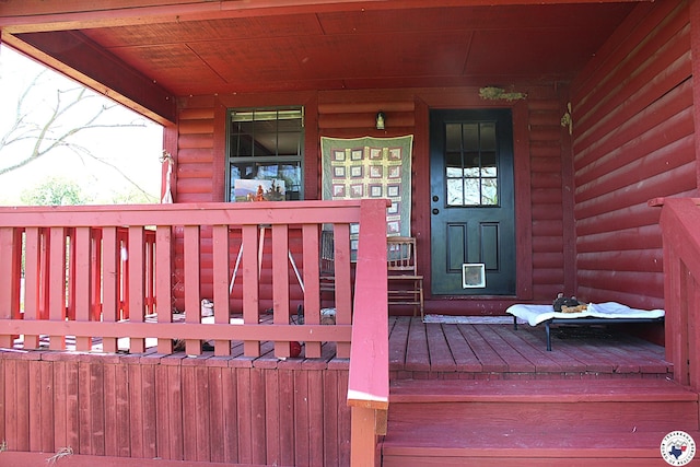 view of exterior entry with covered porch and log veneer siding