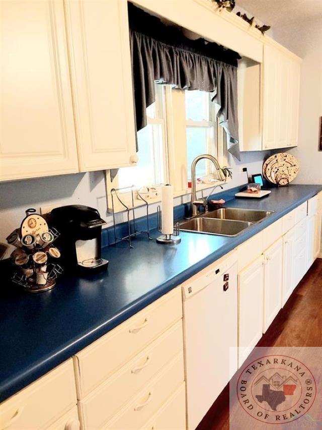 kitchen featuring sink, white cabinetry, white dishwasher, and dark hardwood / wood-style flooring