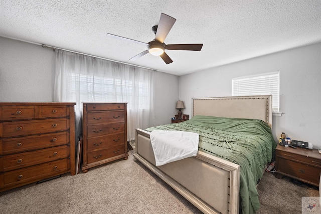 bedroom featuring a textured ceiling, ceiling fan, and light colored carpet