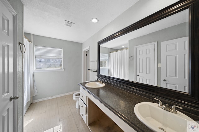 bathroom featuring toilet, baseboards, visible vents, and a sink