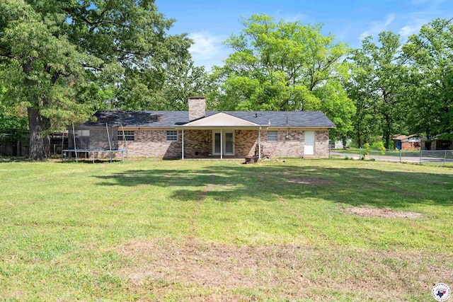 218 Redwood Dr, Texarkana, TX 75501 - back of property with a chimney, fence, a lawn, brick siding, and a trampoline